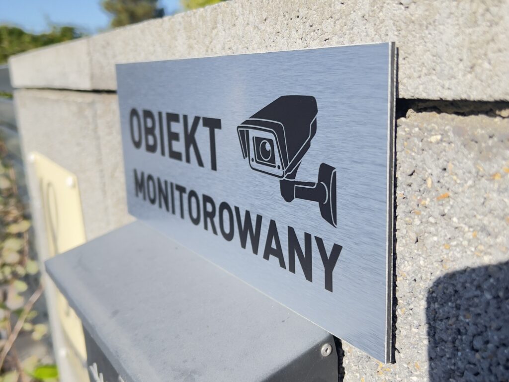 tabliczka wykonana z dibondu srebrnego szczotkowanego z napisem obiekt monitorowany i miniaturką kamery